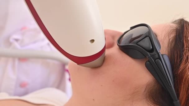 Close-up de remoção de cabelo a laser em uma cara de mulher. O médico remove o cabelo indesejado do paciente acima do lábio com um dispositivo elétrico — Vídeo de Stock