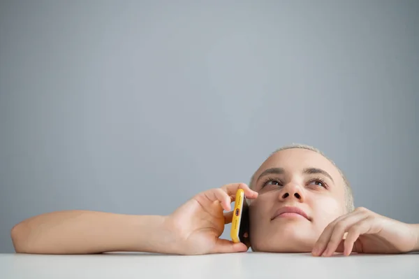 Une jeune femme chère avec une coupe de cheveux courte parle prudemment sur un téléphone portable sur un fond blanc — Photo