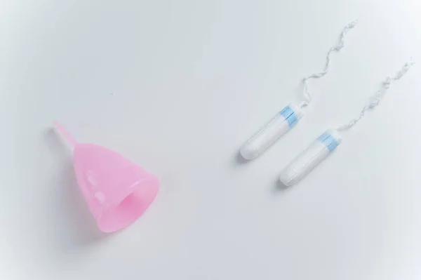 Copo menstrual rosa e tampões em um fundo branco. Comparação de produtos de higiene pessoal para mulheres durante a menstruação — Fotografia de Stock