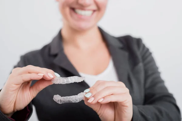 Uma mulher está segurando um protetor bucal de plástico transparente. Ortodontistas mordem dispositivo de correção — Fotografia de Stock
