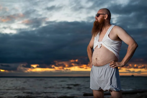 Umorismo ritratto di un uomo brutale in posa sulla spiaggia al tramonto — Foto Stock