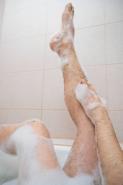 Divertida foto de un hombre tomando un baño relajante. Primer plano de los pies masculinos en un baño de burbujas. Vista superior —  Fotos de Stock