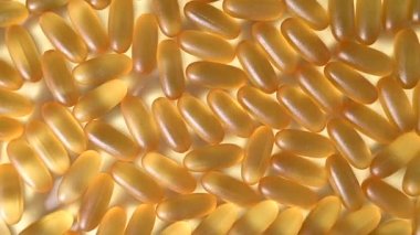 Altın omega üç kapsülüne yakın çekim. Beslenme takviyesi balık yağı beyaz arka planda döner