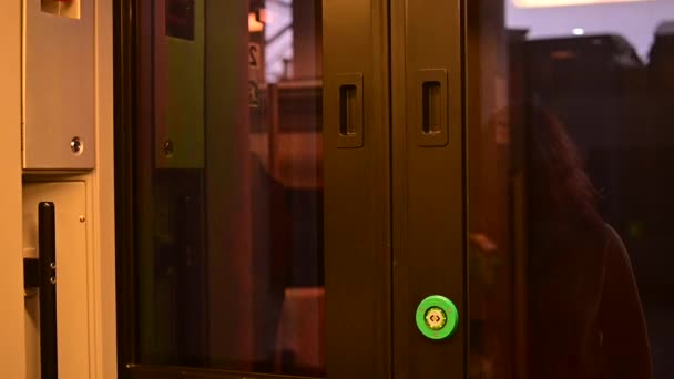 Biała rudowłosa kobieta wchodzi do wagonu pociągowego naciskając przycisk, aby otworzyć drzwi — Wideo stockowe