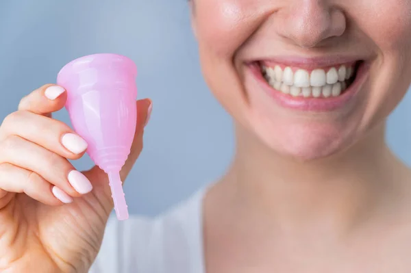 Közelkép portré mosolygó fehér nő kezében rózsaszín menstruációs csésze fehér háttér. Alternatív tamponok és párnák kritikus napokon. — Stock Fotó