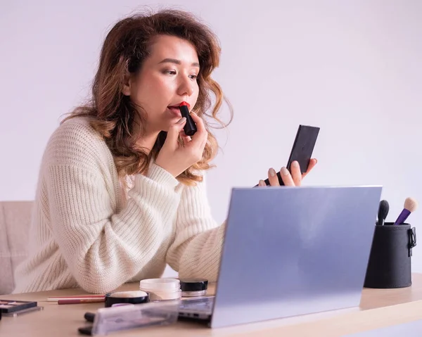 Belle femme caucasienne appliquant rouge à lèvres et regarder des tutoriels de maquillage sur ordinateur portable. — Photo