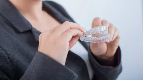 A woman is holding a transparent plastic mouth guard. Orthodontists bite correction device — Stock Photo, Image