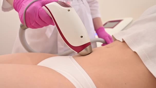 Una mujer en un salón de belleza en un procedimiento para la depilación láser de la vegetación no deseada en el abdomen — Vídeos de Stock