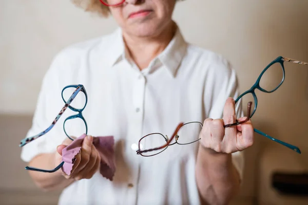 Літня кавказька жінка вибирає окуляри зі своєї колекції. — стокове фото
