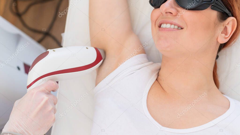 Doctor doing laser hair removal on a womans armpit in the salon. An alternative way to permanently remove unwanted body hair