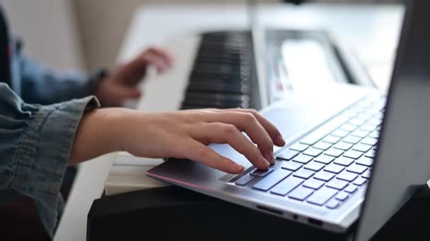 Close-up de mãos femininas no piano elétrico. Uma mulher está aprendendo a tocar o sintetizador em um laptop — Vídeo de Stock