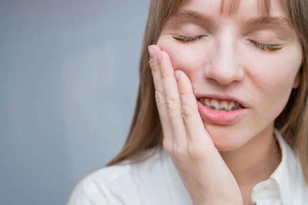 Diş teli yüzünden acı çeken kızıl saçlı bir kızın yakın plan portresi. Genç kadın ısırığı ortodontik aletle düzeltiyor.. — Stok fotoğraf