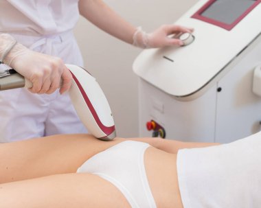 Profesyonel güzellik salonundaki bir kadın, lazer tüyü çıkararak bikini bölgesindeki istenmeyen bitkileri temizliyor.