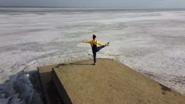 Mujer caucásica haciendo yoga en el muelle del lago congelado. — Vídeos de Stock