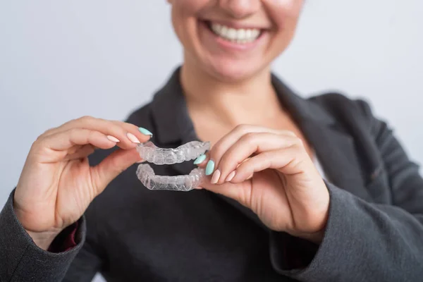 Une femme tient un protège-dents en plastique transparent. Orthodontistes morsure dispositif de correction — Photo