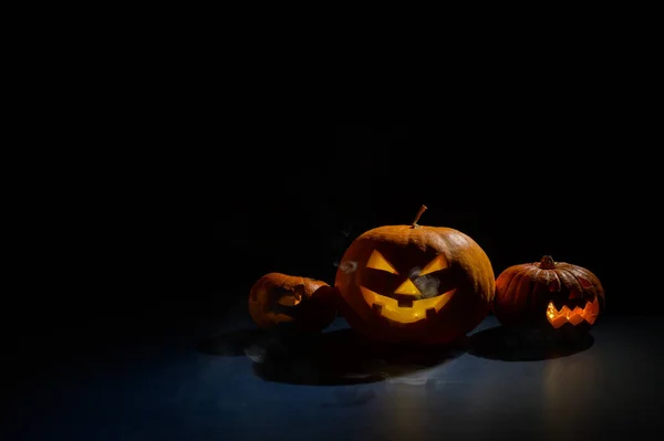 Abóboras com caretas esculpidas e velas no interior no escuro para o dia das bruxas. Jack o latern em fumaça. — Fotografia de Stock