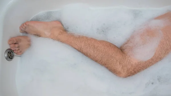 Αστεία φωτογραφία ενός άντρα να κάνει ένα χαλαρωτικό μπάνιο. Κοντινό πλάνο αρσενικών ποδιών σε αφρόλουτρο. Άνω όψη — Φωτογραφία Αρχείου