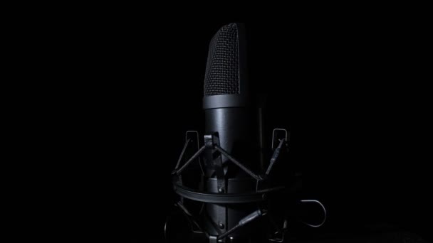 Um close-up de um microfone rotativo contra um fundo preto. Espaço de cópia. — Vídeo de Stock