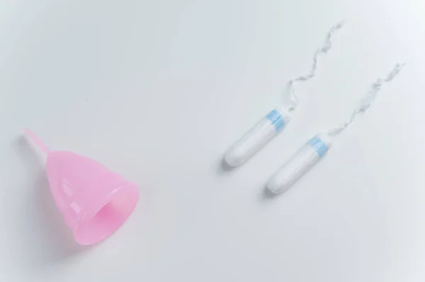 Coupe menstruelle rose et tampons sur fond blanc. Comparaison des produits d'hygiène personnelle pour les femmes pendant les règles — Photo