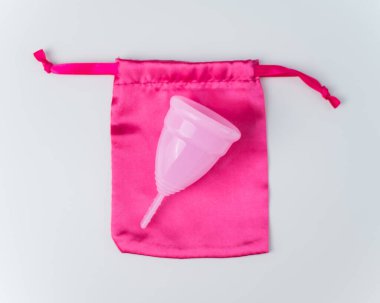 Pembe regl kupası ve beyaz arka planda ipek çanta. Boşluğu kopyala