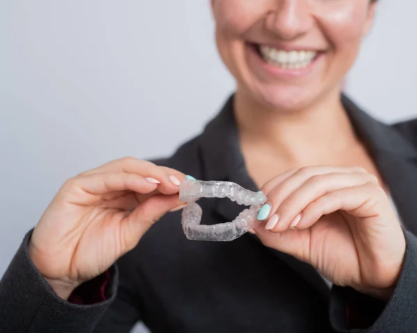 Une femme tient un protège-dents en plastique transparent. Orthodontistes morsure dispositif de correction — Photo