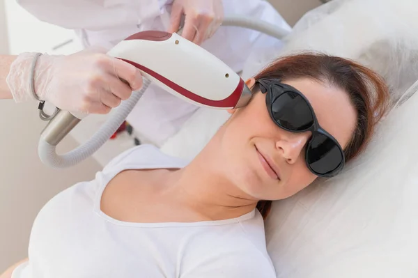 The doctor makes laser hair removal on the face of a woman in the salon. An alternative way to permanently remove unwanted hair