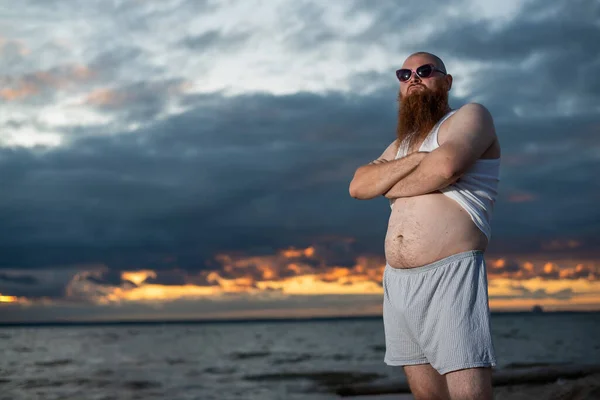 Umorismo ritratto di un uomo brutale in posa sulla spiaggia al tramonto — Foto Stock