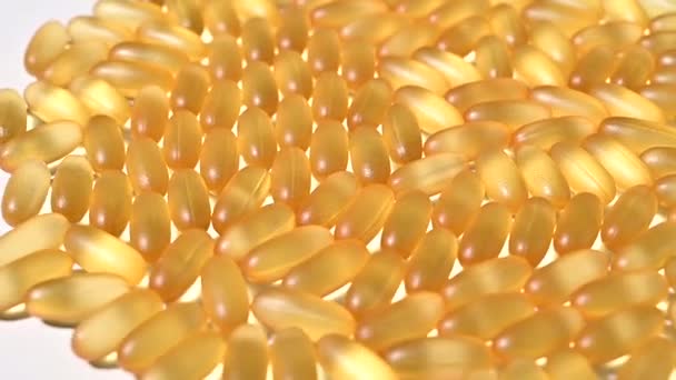 Detailní záběr průhledných žlutých tobolek na točícím se bílém stole. Doplňky stravy obsahující omega 3 a rybí tuk — Stock video