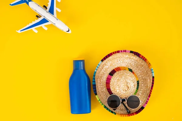 飞机上的太阳镜和一管黄色背景的防晒霜。暑假的概念. — 图库照片