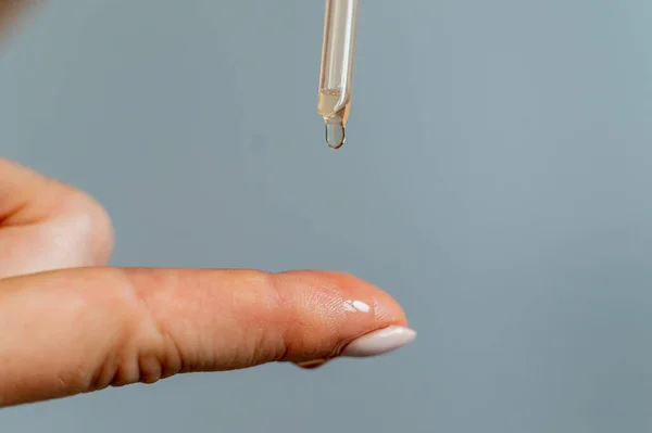 Close-up vrouw druipende olie op haar vinger over witte achtergrond — Stockfoto