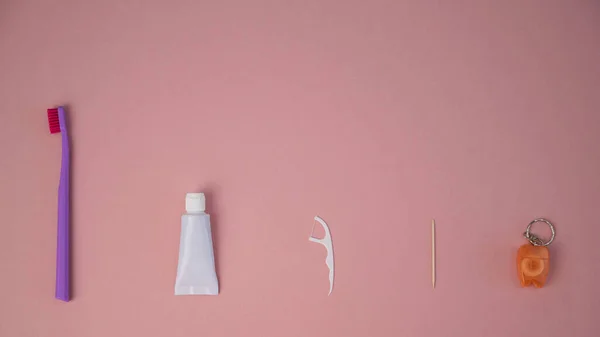 Productos de higiene oral sobre fondo rosa. Cepillo de dientes pasta dental hilo dental y palillo de dientes. Copiar espacio. — Foto de Stock