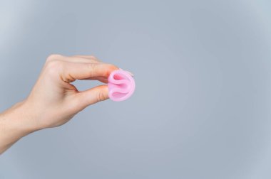 Beyaz arka planda katlanmış adet bardağını tutan kadın..