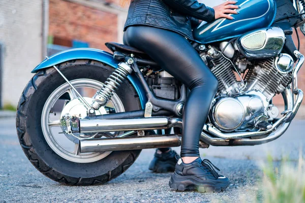 Une femme en legging en cuir est assise sur une moto. fermer uo de jambes féminines sur un vélo — Photo