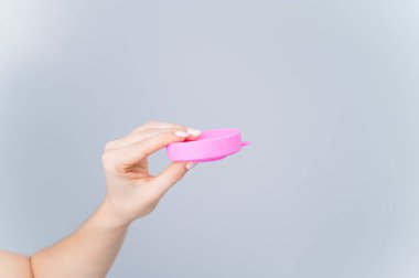 Beyaz arka plandaki regl bardağını sterilize etmek için katlanmış konteynır.