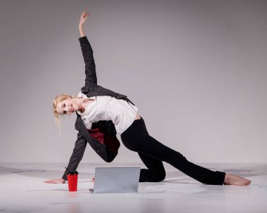 İş elbisesi giymiş bir balerin dizüstü bilgisayara poz verir ve kahve içer. Bilgisayar başında esnek bir kadın çalışıyor.