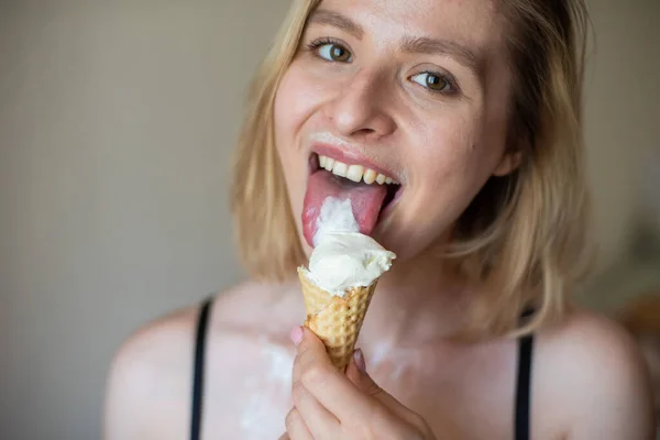 Сексуальная блондинка лижет вафельный рожок. Мороженое тает, эротически просачиваясь через тело привлекательной женщины. Красивая девушка, размазанная мороженым. — стоковое фото