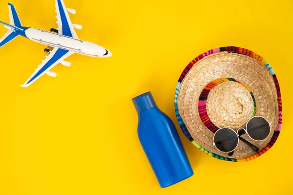 飞机上的太阳镜和一管黄色背景的防晒霜。暑假的概念. — 图库照片