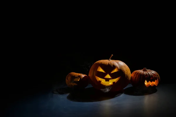 Dýně s vyřezávanými grimasami a svíčkami ve tmě na Halloween. Jack o latern in smoke. — Stock fotografie