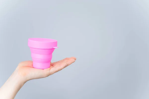 Nő kezében műanyag összecsukható pohár sterilizálni menstruációs csésze fehér háttér. Kényelmes tartály tisztításhoz — Stock Fotó