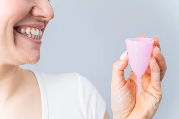 Közelkép portré mosolygó fehér nő kezében rózsaszín menstruációs csésze fehér háttér. Alternatív tamponok és párnák kritikus napokon. — Stock Fotó
