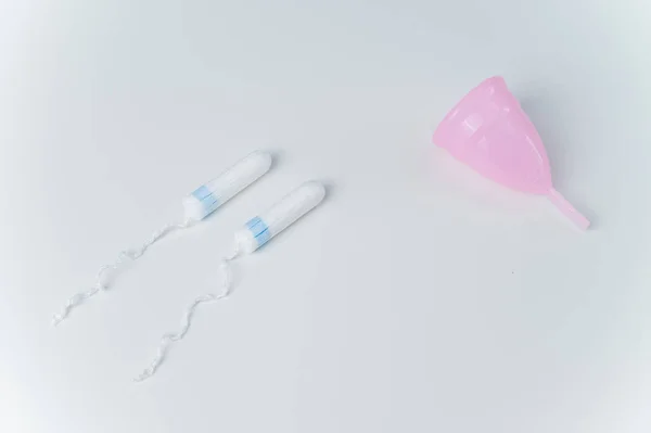 Cangkir menstruasi merah muda dan tampon pada latar belakang putih. Perbandingan produk kebersihan pribadi bagi perempuan selama menstruasi — Stok Foto