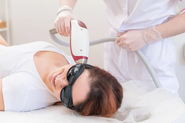 Der Arzt entfernt einer Frau im Salon per Laser die Haare im Gesicht. Eine alternative Möglichkeit, unerwünschte Haare dauerhaft zu entfernen — Stockfoto