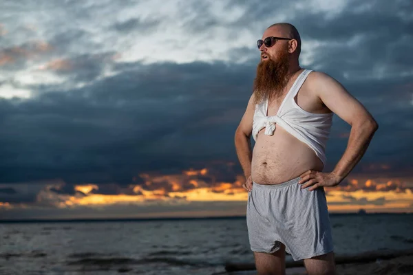 Umorismo ritratto di un uomo brutale in posa sulla spiaggia al tramonto — Foto Stock