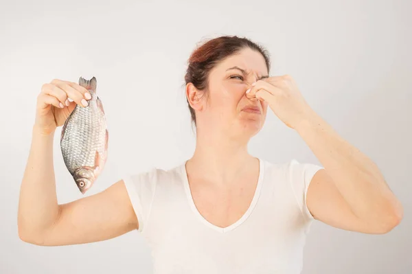 Mulher caucasiana se opõe ao cheiro nojento de peixe. Uma metáfora para a saúde das mulheres e higiene íntima. — Fotografia de Stock