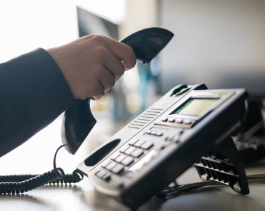 Sabit bir telefondan bir numarayı arayan kadın bir ofis çalışanının eli yakın çekim. Meçhul kadın sekreter telefonda.