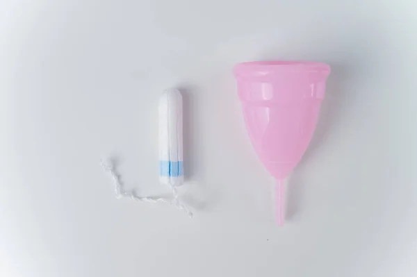 Rosa Menstruationstasse und Tampon auf weißem Hintergrund. Verschiedene Hygieneprodukte während der Menstruation — Stockfoto