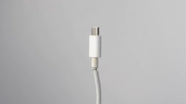 Beyaz arkaplanda dönen bir cep telefonu tipini şarj etmek için kopmuş kablo.