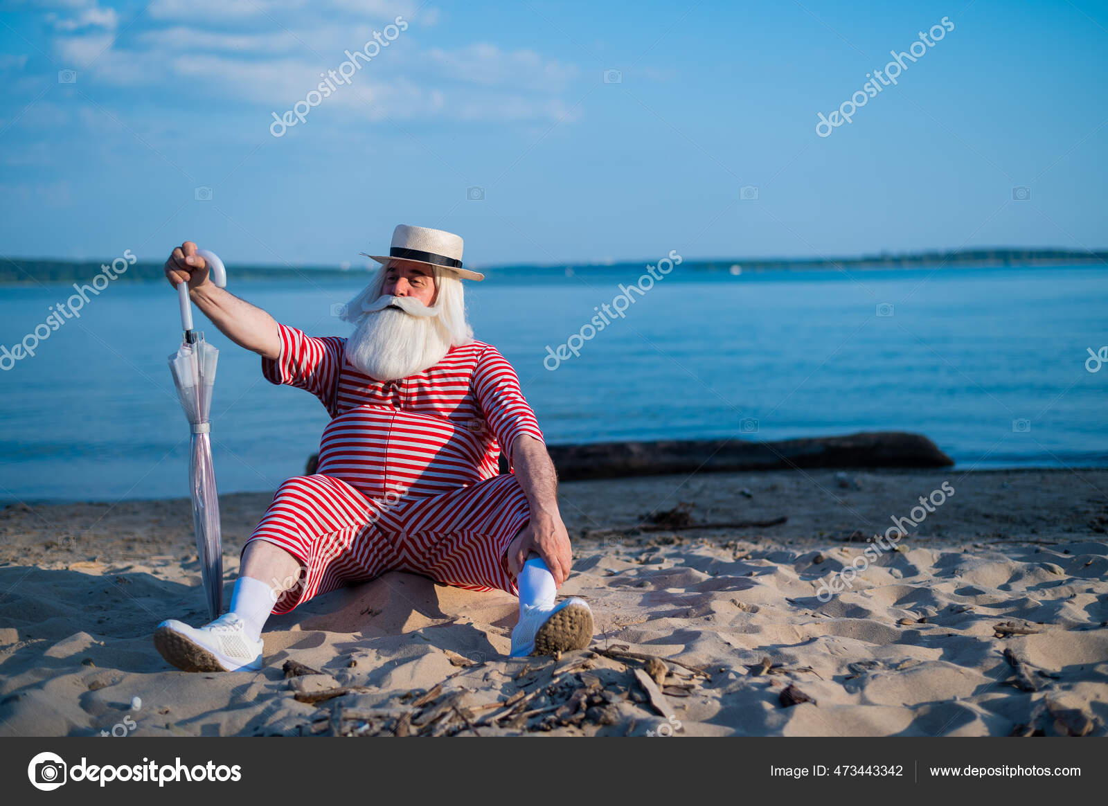 An old man in a classic bathing suit walks along the beach with an