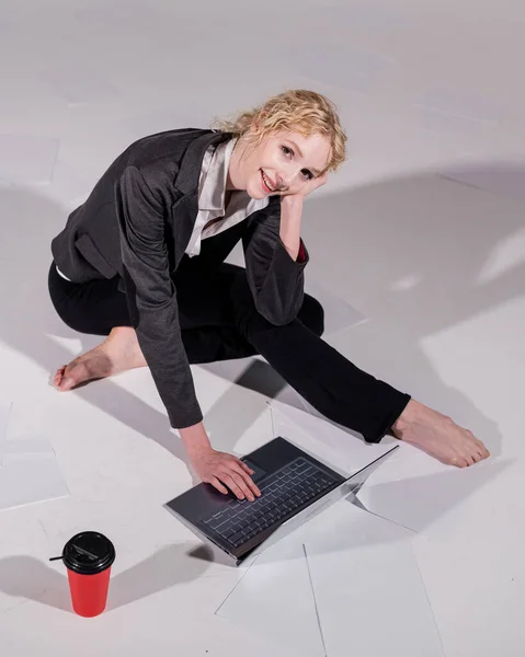 Μια μπαλαρίνα ντυμένη με επαγγελματικό κοστούμι ποζάρει για ένα λάπτοπ και πίνει καφέ. Ευέλικτη γυναίκα εργάζεται στον υπολογιστή — Φωτογραφία Αρχείου
