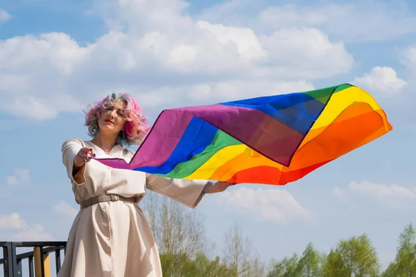 Mujer caucásica con cabello rizado con bandera lgbt. Mujer lesbiana sosteniendo una bandera de arco iris al aire libre —  Fotos de Stock